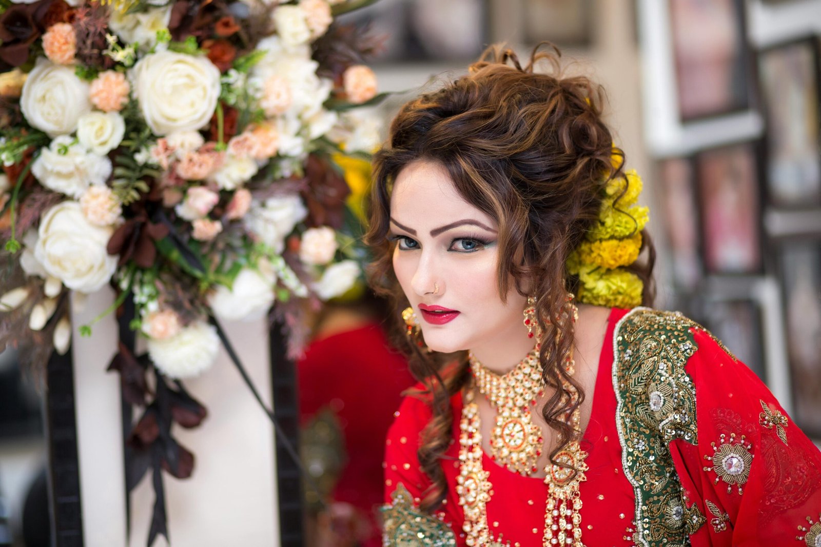 Beautiful South Asian bride in red traditional attire with floral bouquet, showcasing exquisite cultural style.