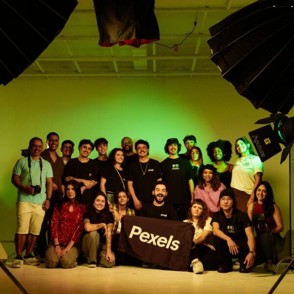 Group of diverse individuals posing with Pexels banner in a photo studio.